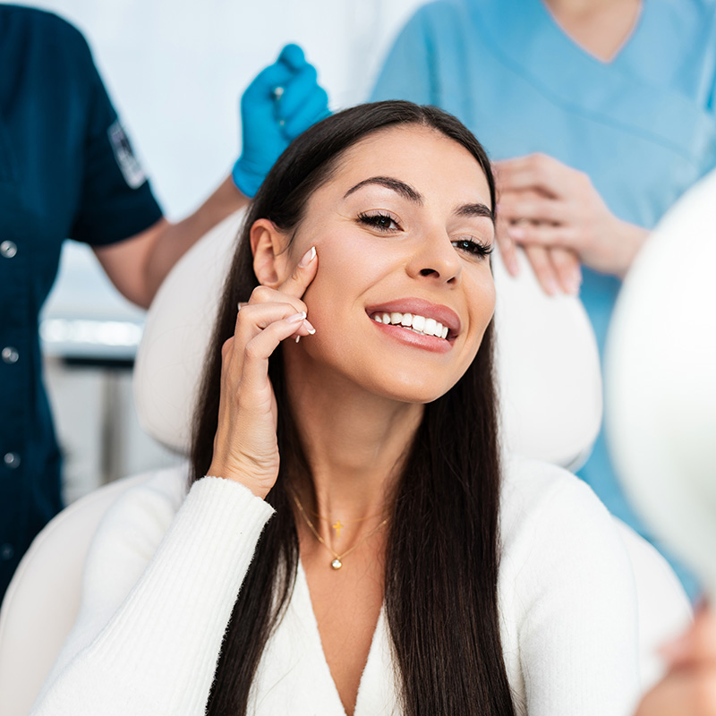 woman looking at her face after receiving injectable filler